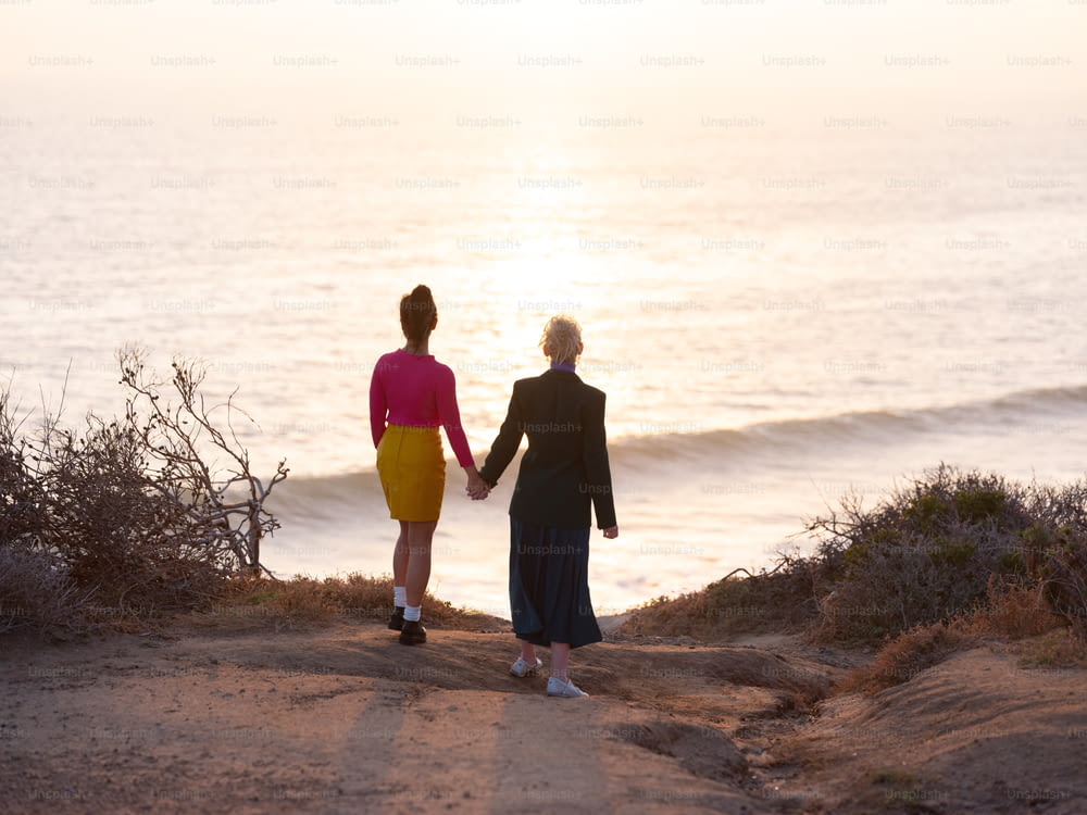 Un par de mujeres caminando por un camino de tierra junto al océano