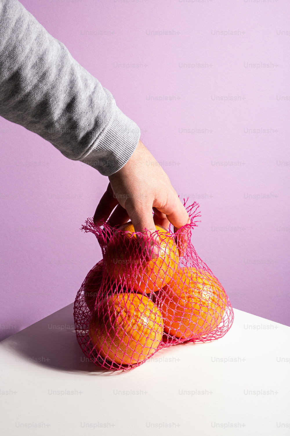 uma pessoa segurando um saco de laranjas em uma mesa