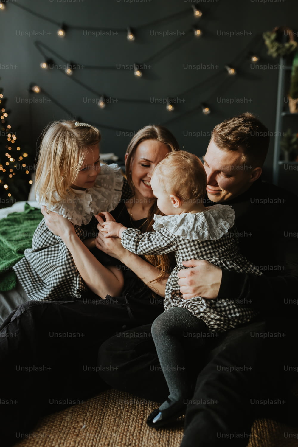 a family sitting on a bed with a christmas tree in the background
