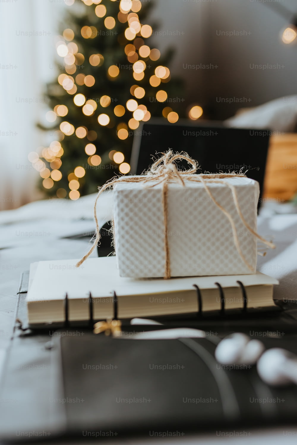 크리스마스 트리 옆에 있는 책 위에 앉아 있는 하얀 선물