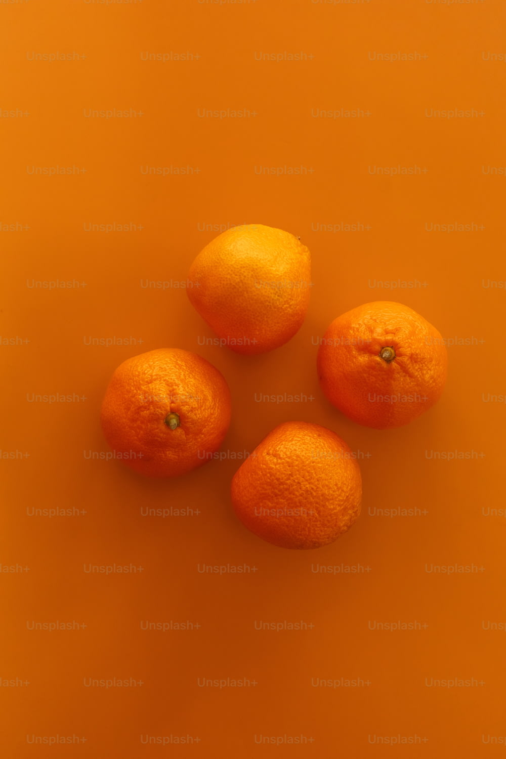 four oranges sitting on top of an orange surface