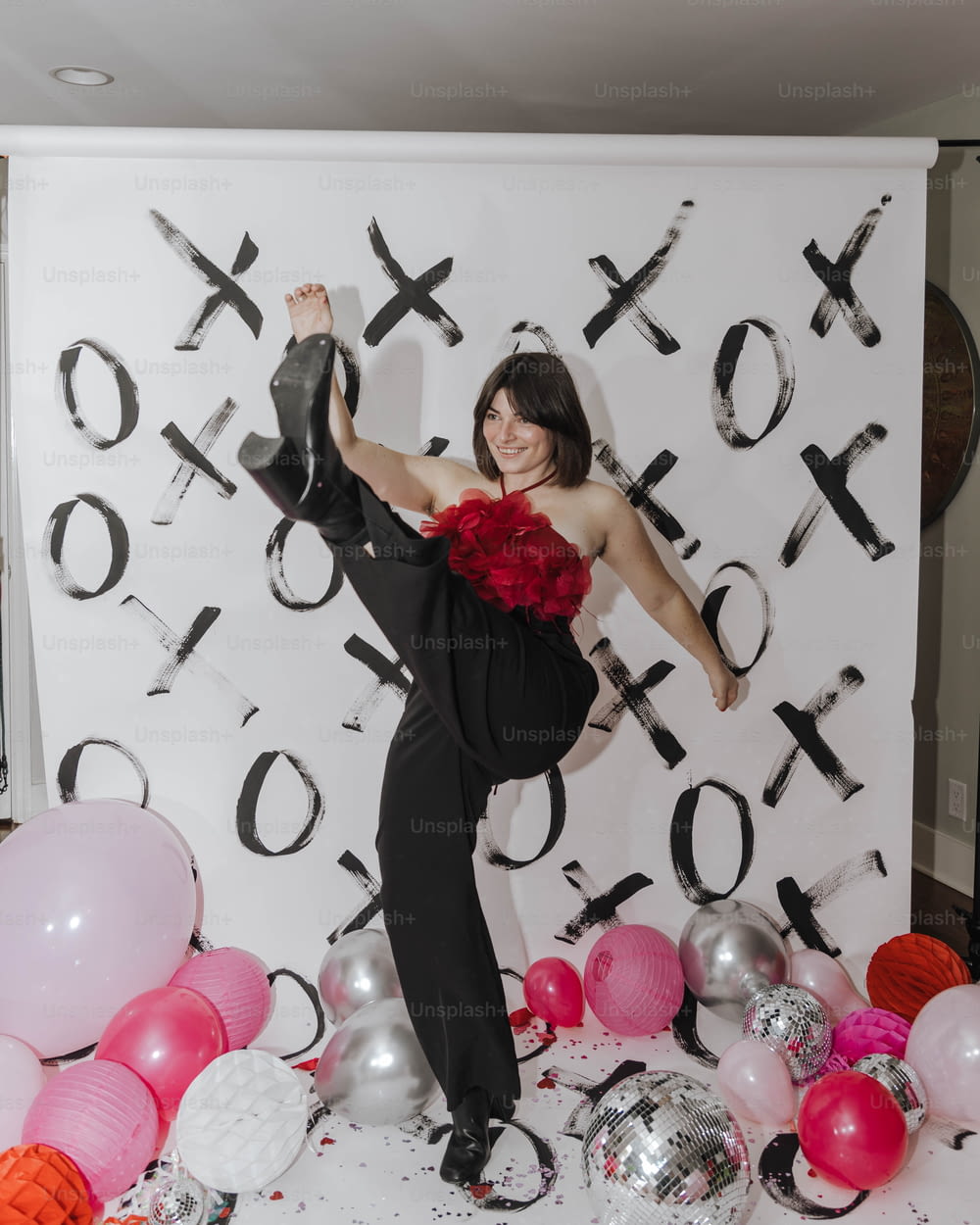 a woman posing in front of a backdrop of balloons