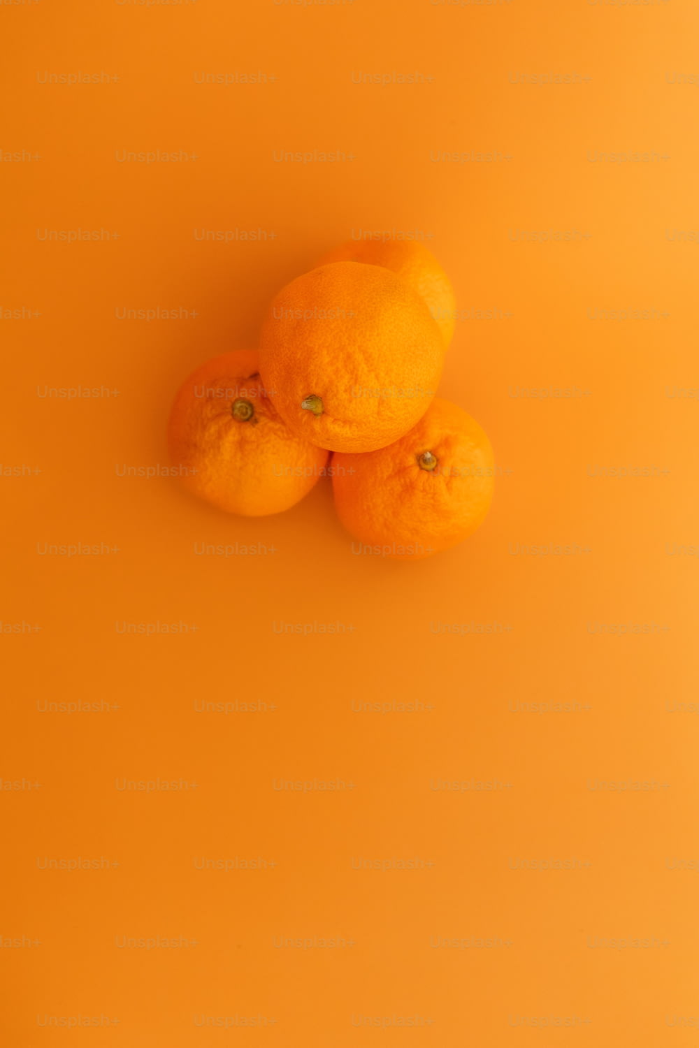 Tres naranjas sentadas encima de una superficie amarilla