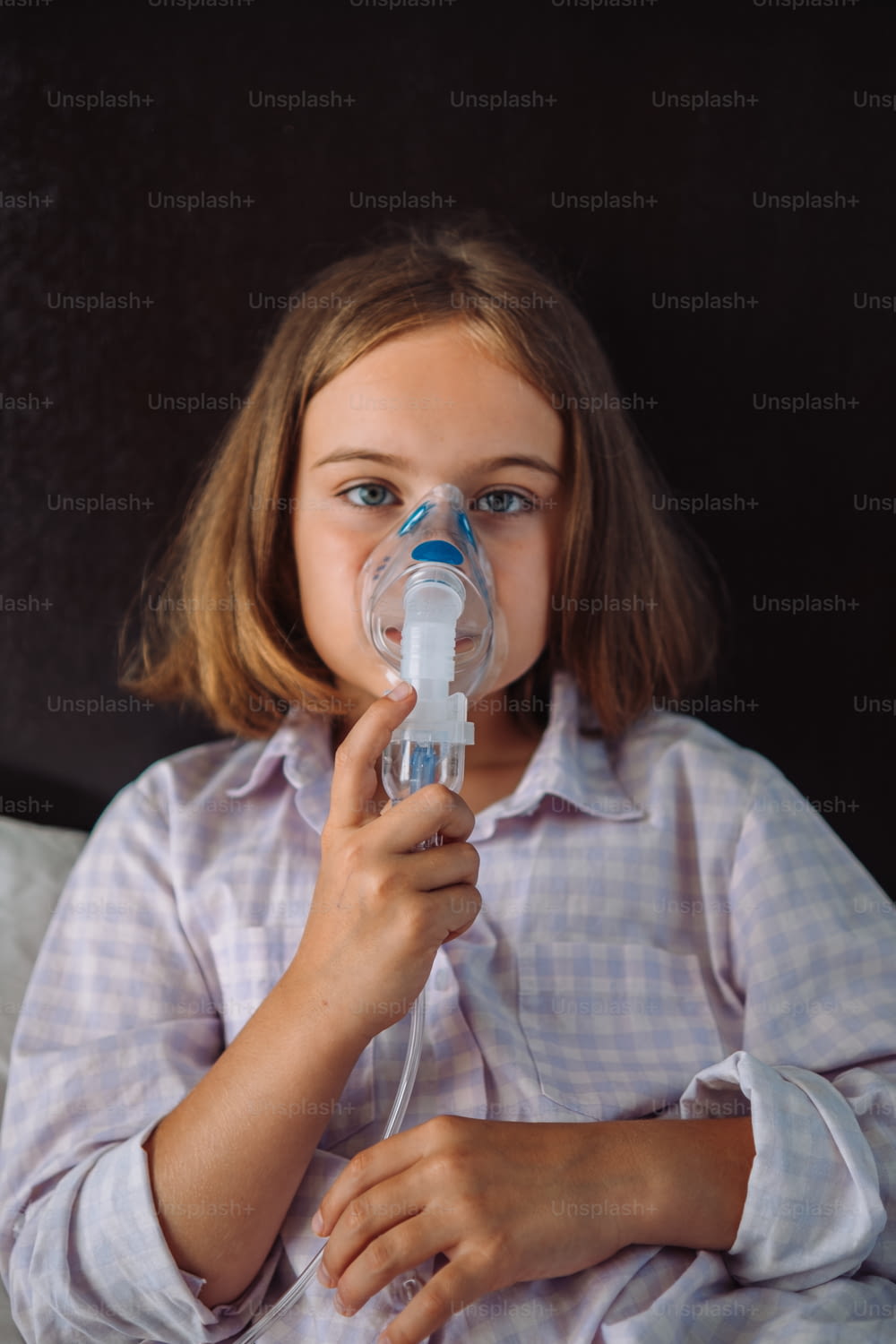 uma menina com um dispositivo de respiração em sua boca