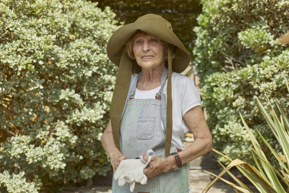 an older woman wearing a hat and gardening gloves