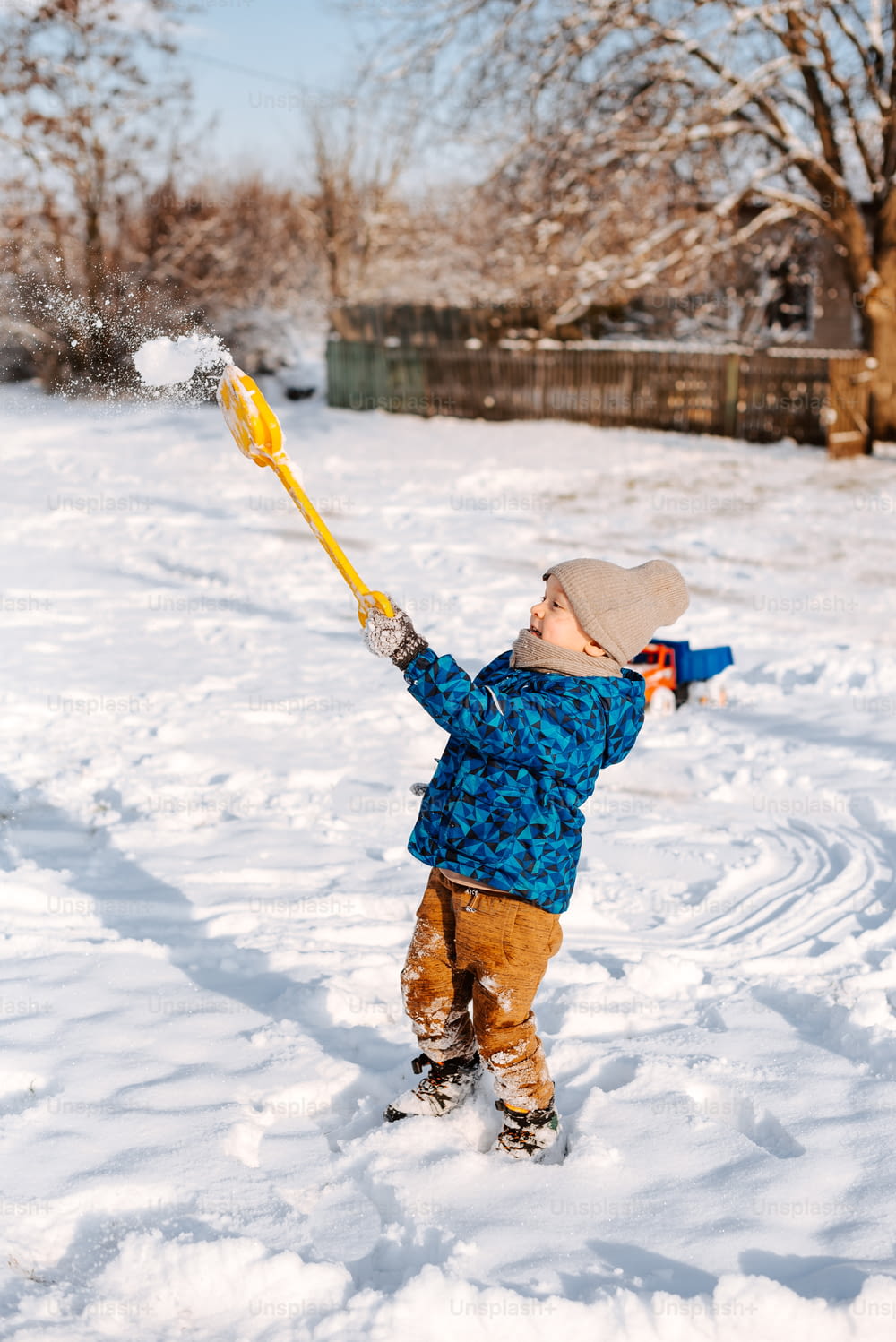 a young boy playing in the snow with a stick
