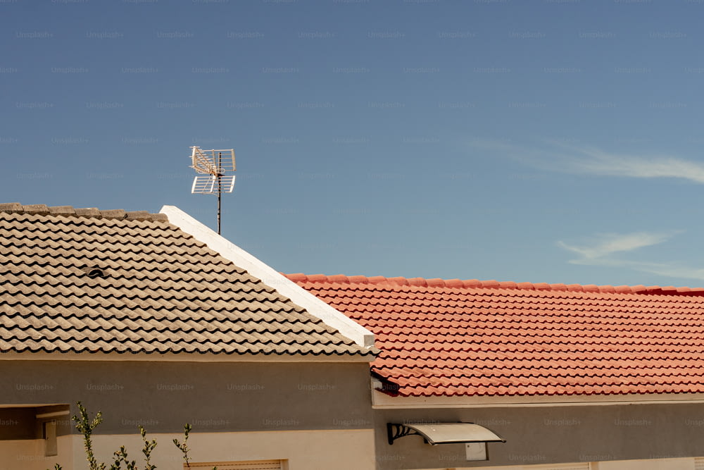 une maison avec un toit de tuiles rouges et une girouette au-dessus