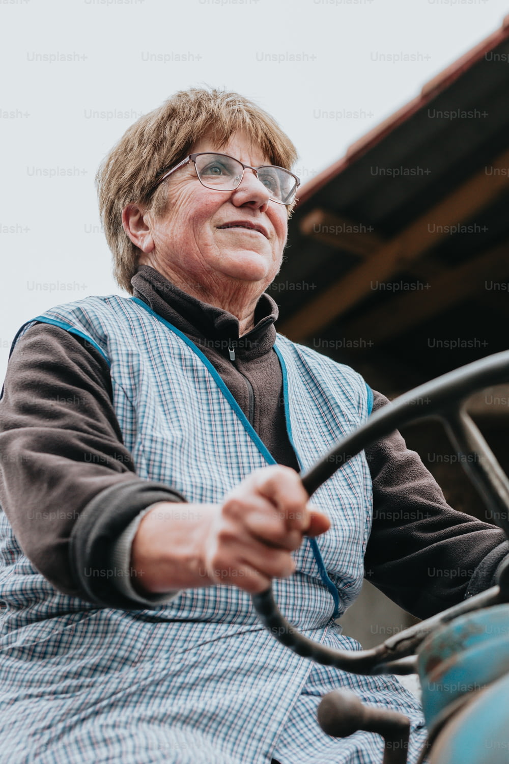 Eine ältere Frau fährt einen Traktor mit den Händen am Lenkrad