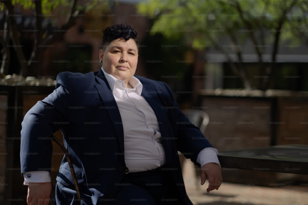 a woman sitting on a bench wearing a suit and tie