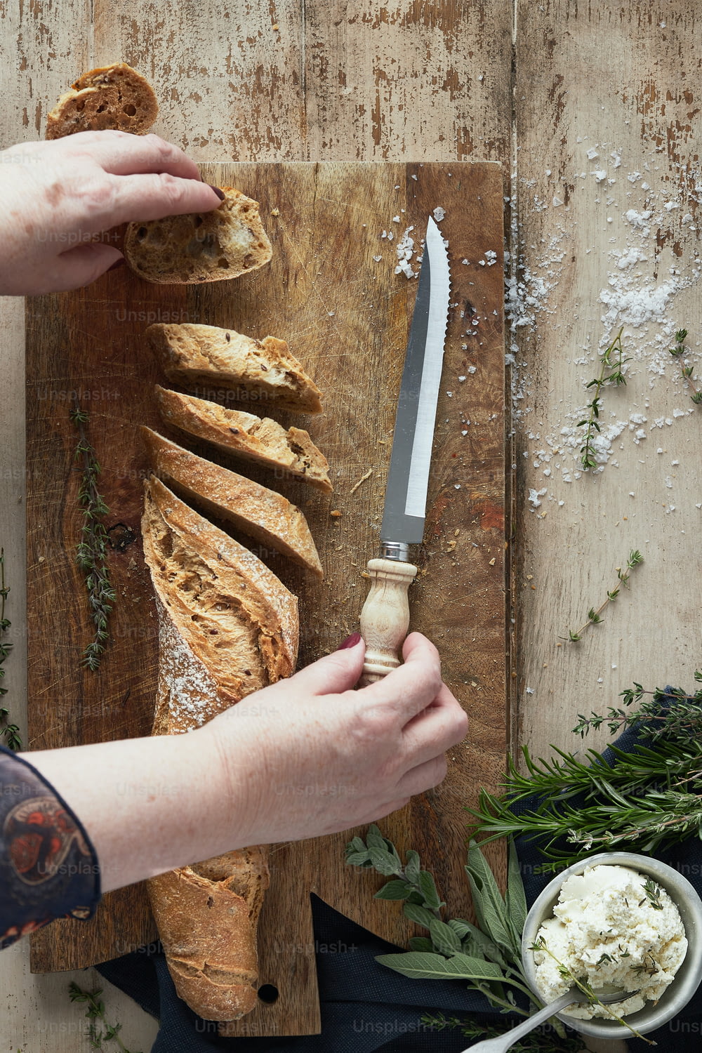 a person cutting bread with a knife on a cutting board
