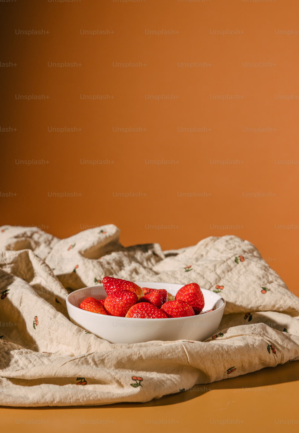 Eine Schüssel Erdbeeren sitzt auf einem Handtuch