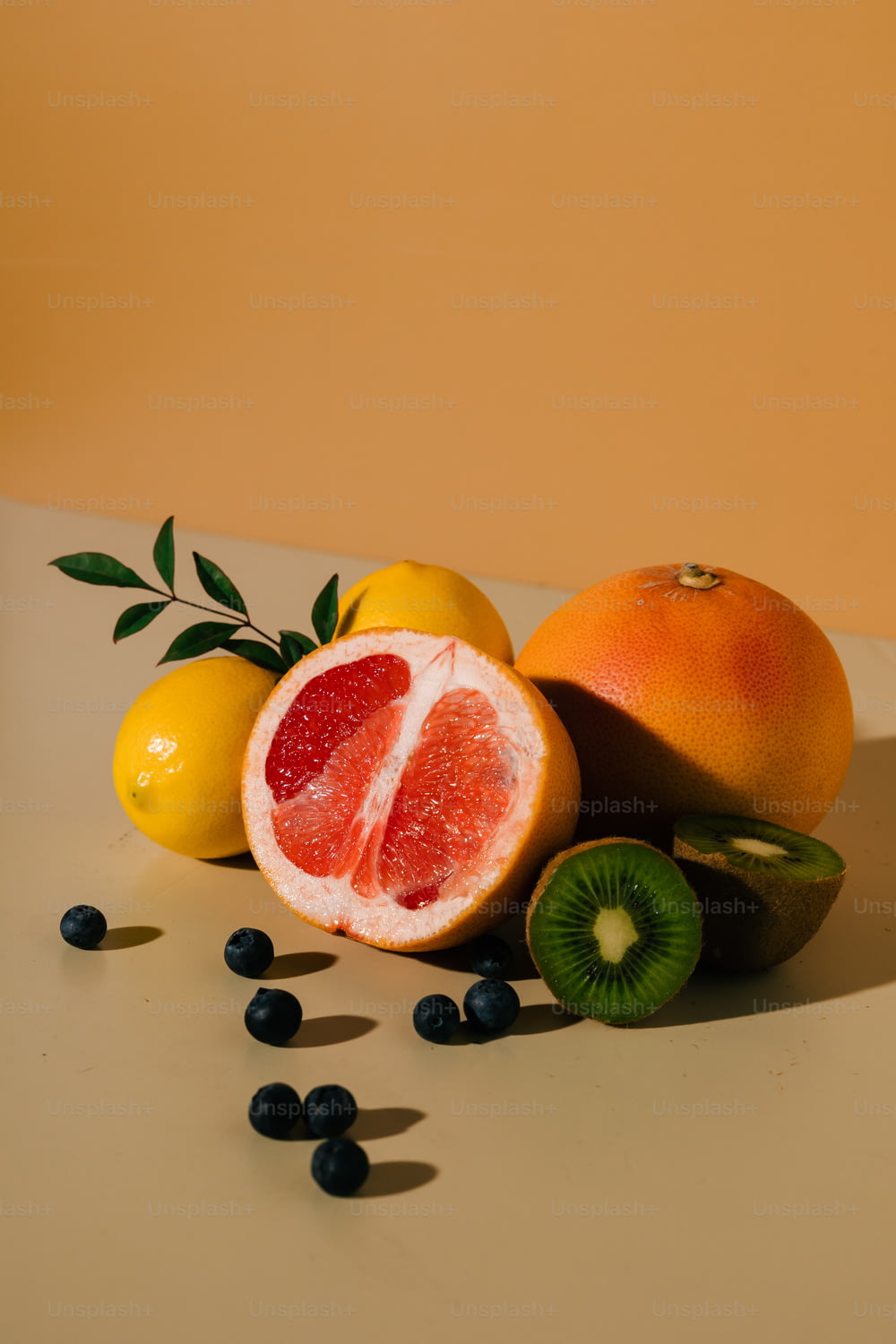a grapefruit, orange, kiwi, and lemons on a table