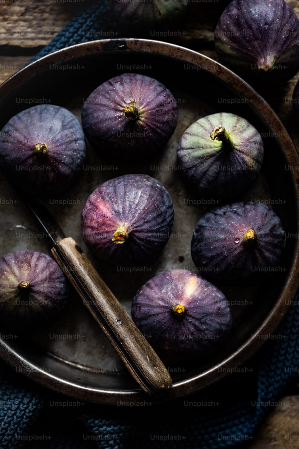 a bowl filled with purple figs on top of a table