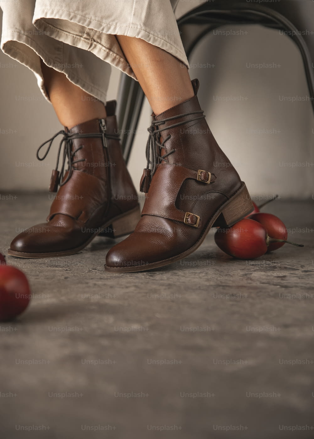 les jambes d’une femme avec des chaussures brunes et des pommes sur le sol