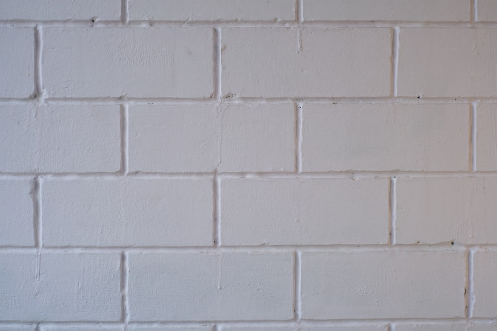 un muro di mattoni bianchi con un segnale di stop rosso su di esso