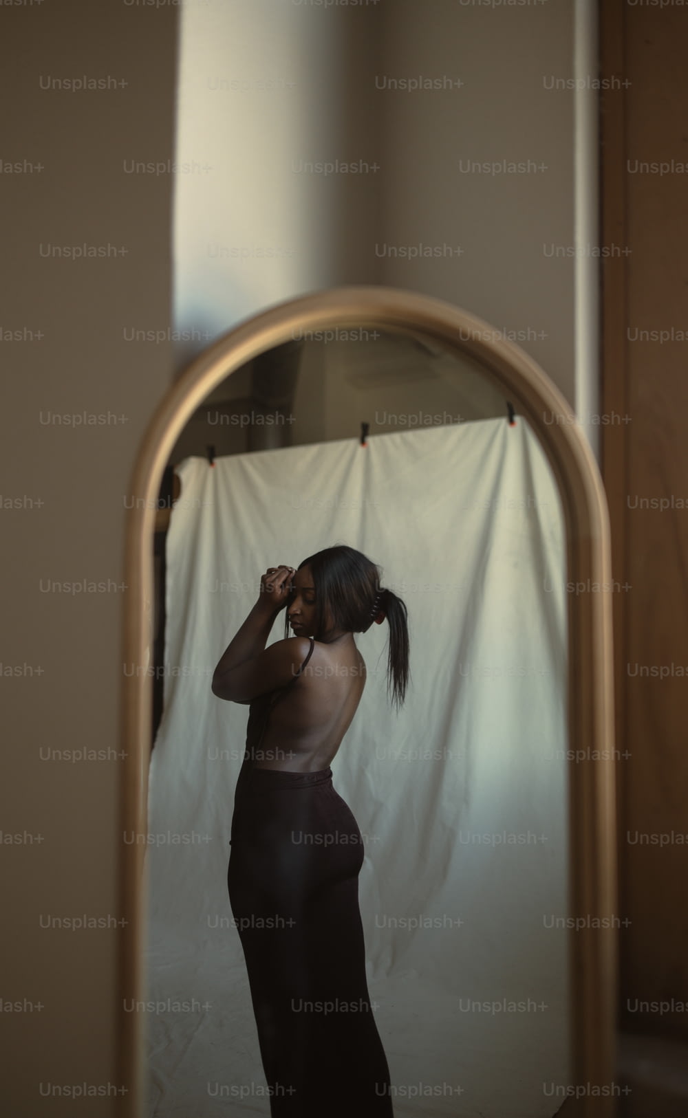 a woman standing in front of a mirror brushing her hair