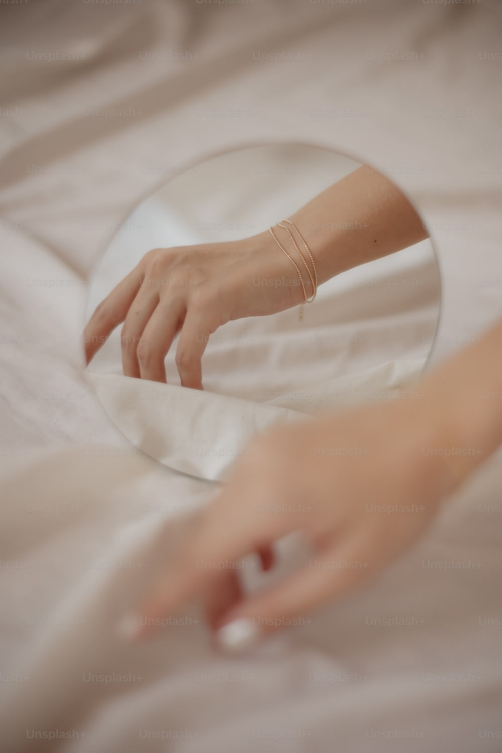 a person's hand touching a mirror on a bed