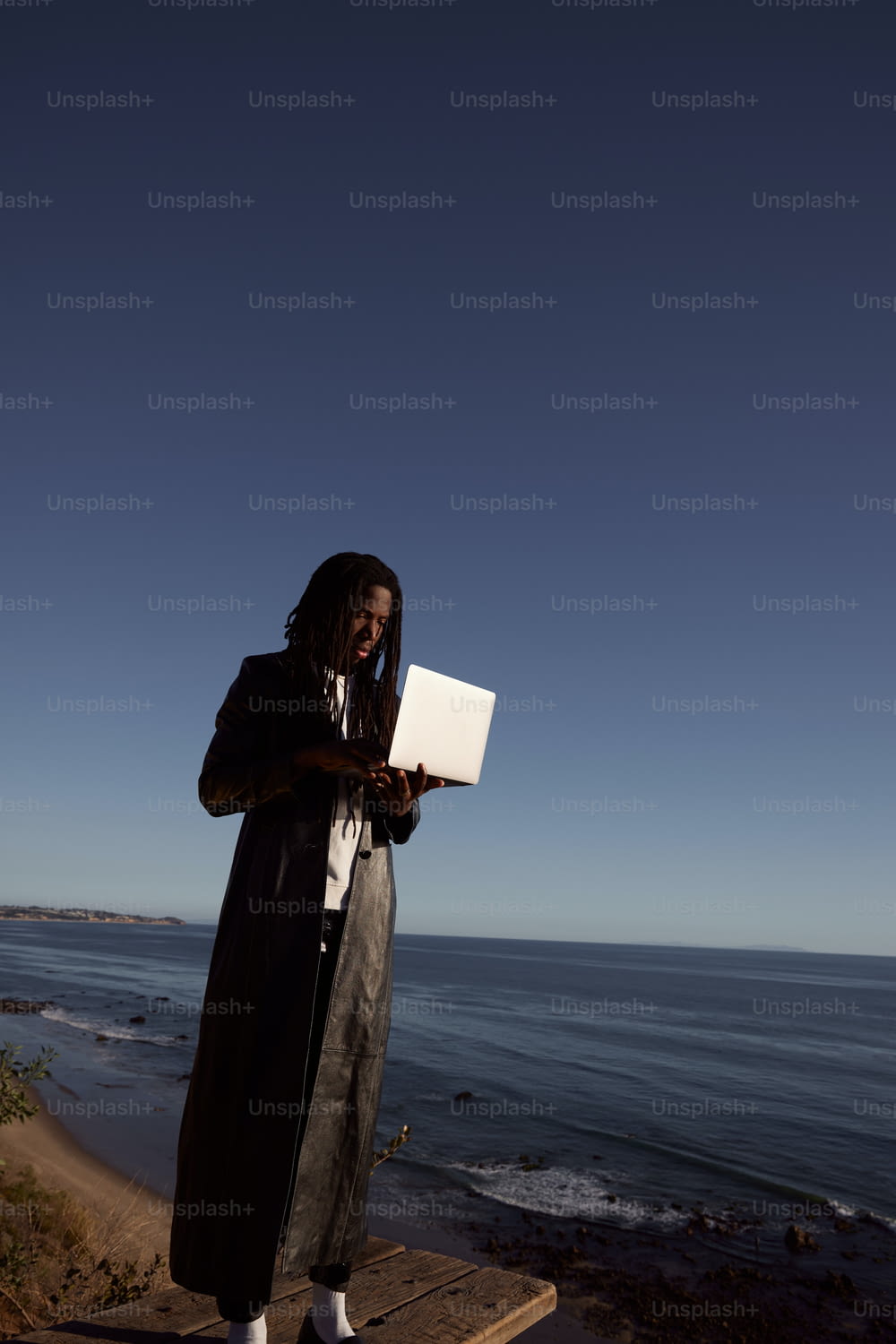 a woman standing on a dock using a laptop computer