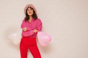 Una donna in una camicia rosa e pantaloni rossi che tiene palloncini