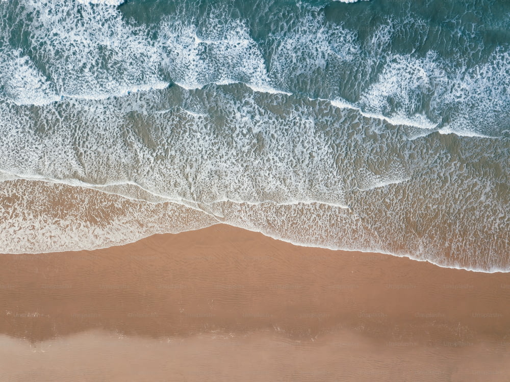 an aerial view of a sandy beach with waves