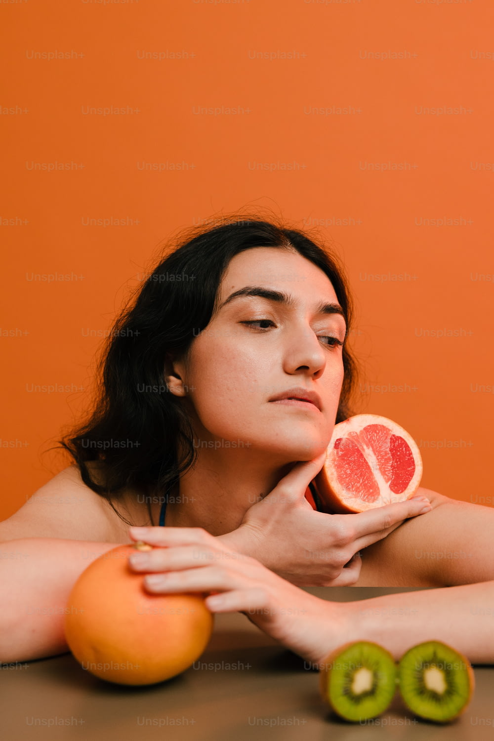 Eine Frau hält eine Grapefruit und eine Kiwi in der Hand
