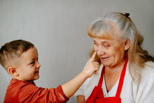 Eine ältere Frau hilft einem kleinen Jungen mit seinen Haaren