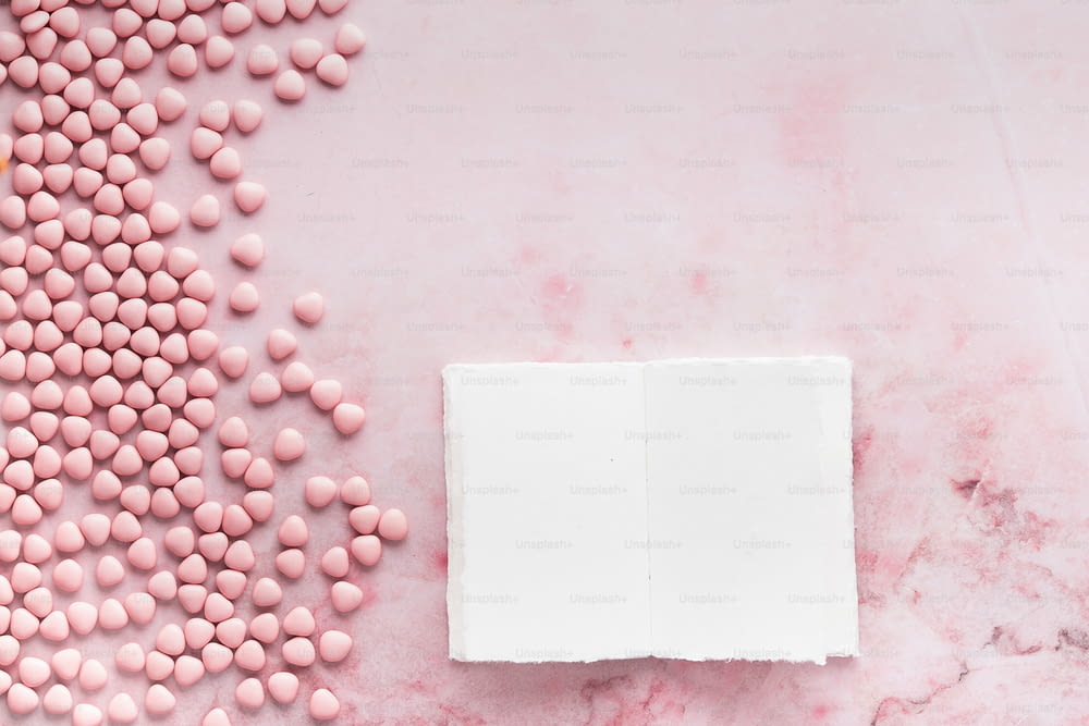 a white box with pink candy on a pink marble surface