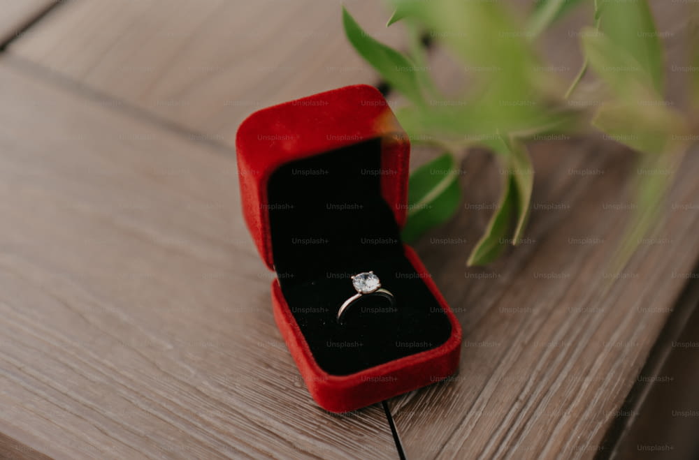 una scatola di anelli di velluto rosso con un diamante bianco in esso