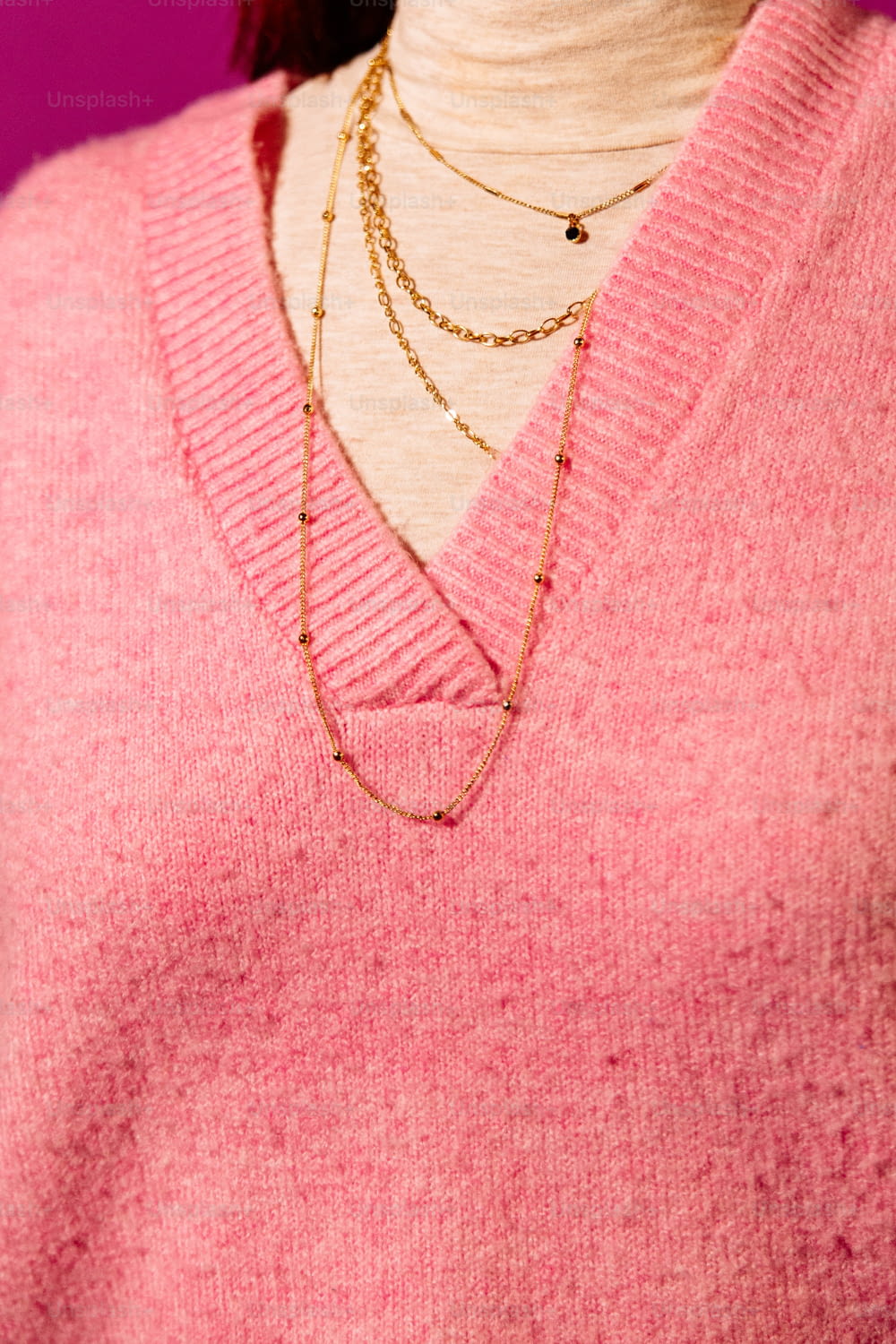 um close up de uma pessoa vestindo um suéter rosa