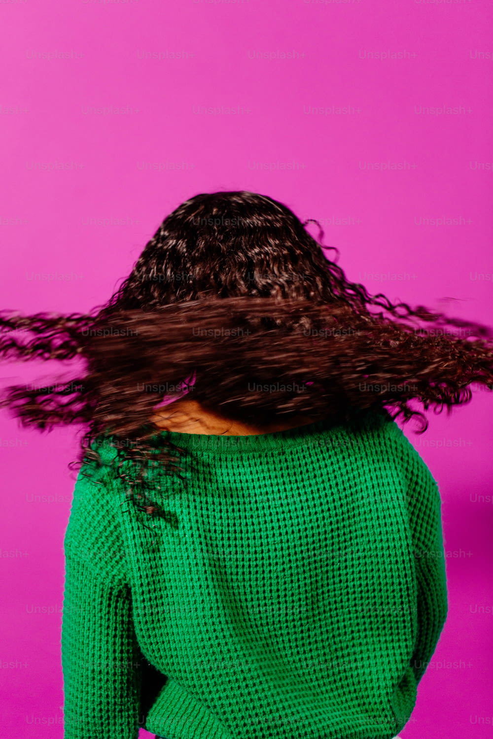 a woman with long hair standing in front of a pink background