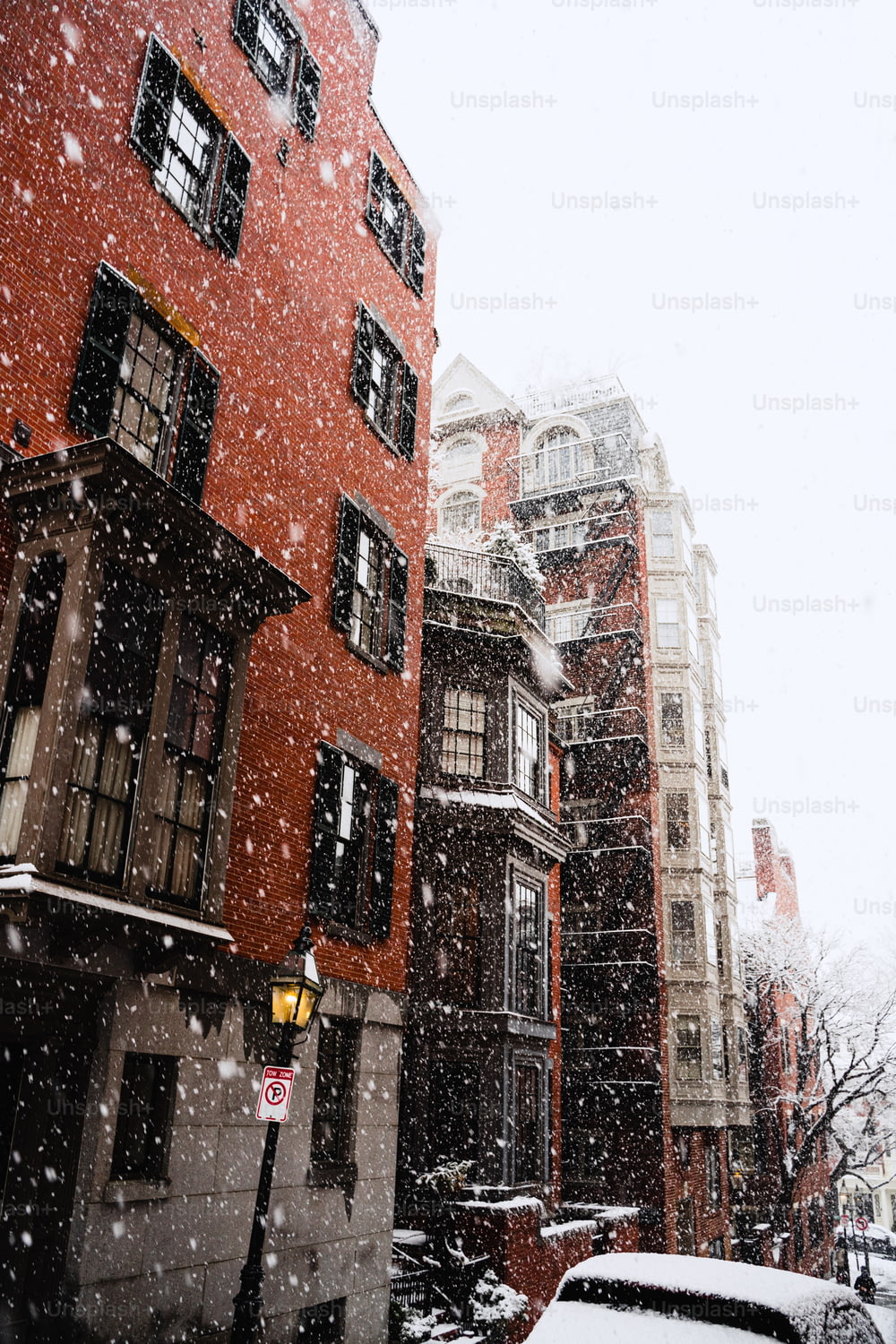 a snowy day in a city with buildings and cars