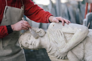 Un hombre está trabajando en una estatua de una mujer