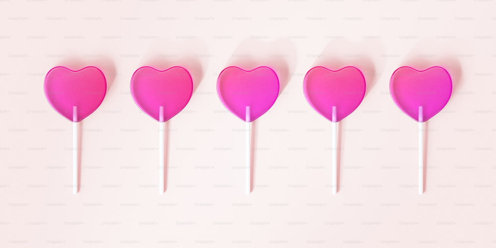 a row of heart shaped lollipops on a pink background