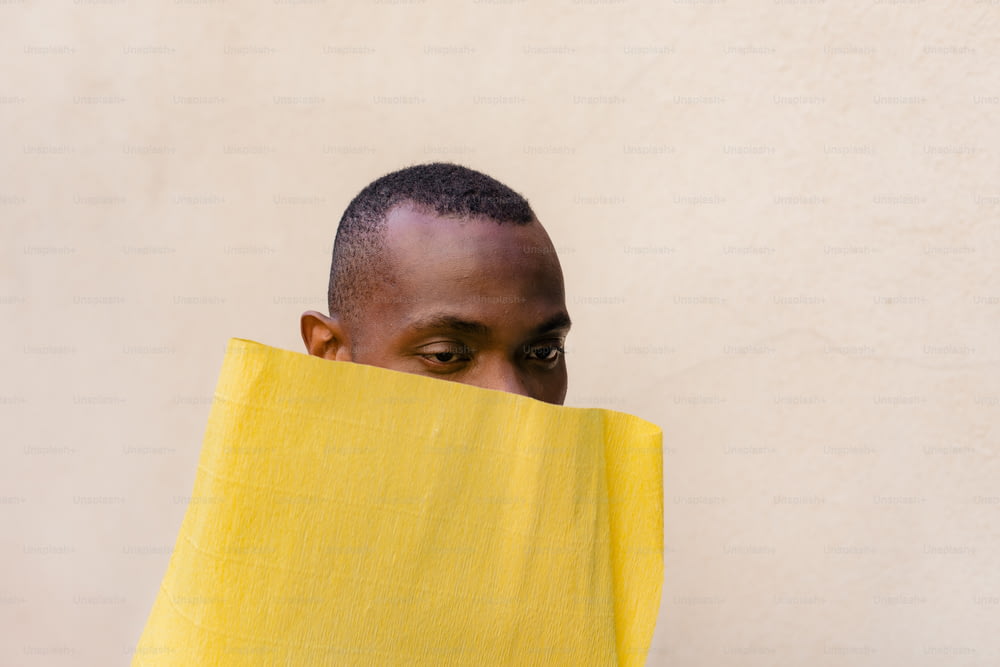 Un homme cachant son visage derrière un tissu jaune