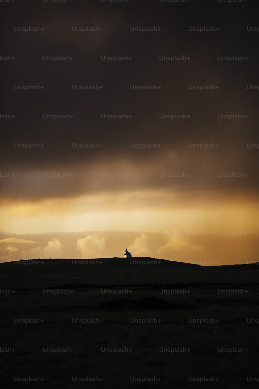 a lone horse standing on top of a hill under a cloudy sky