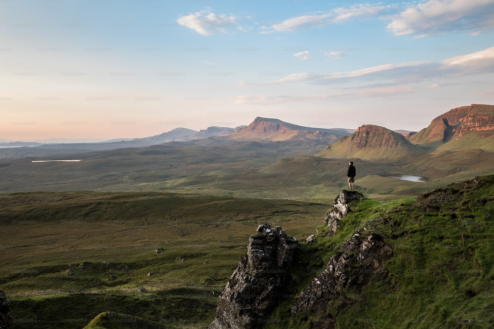 una persona in piedi sulla cima di una collina verde
