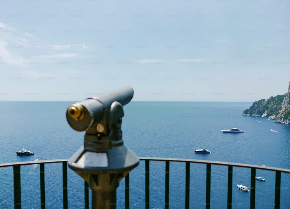 a telescope on a railing overlooking a body of water