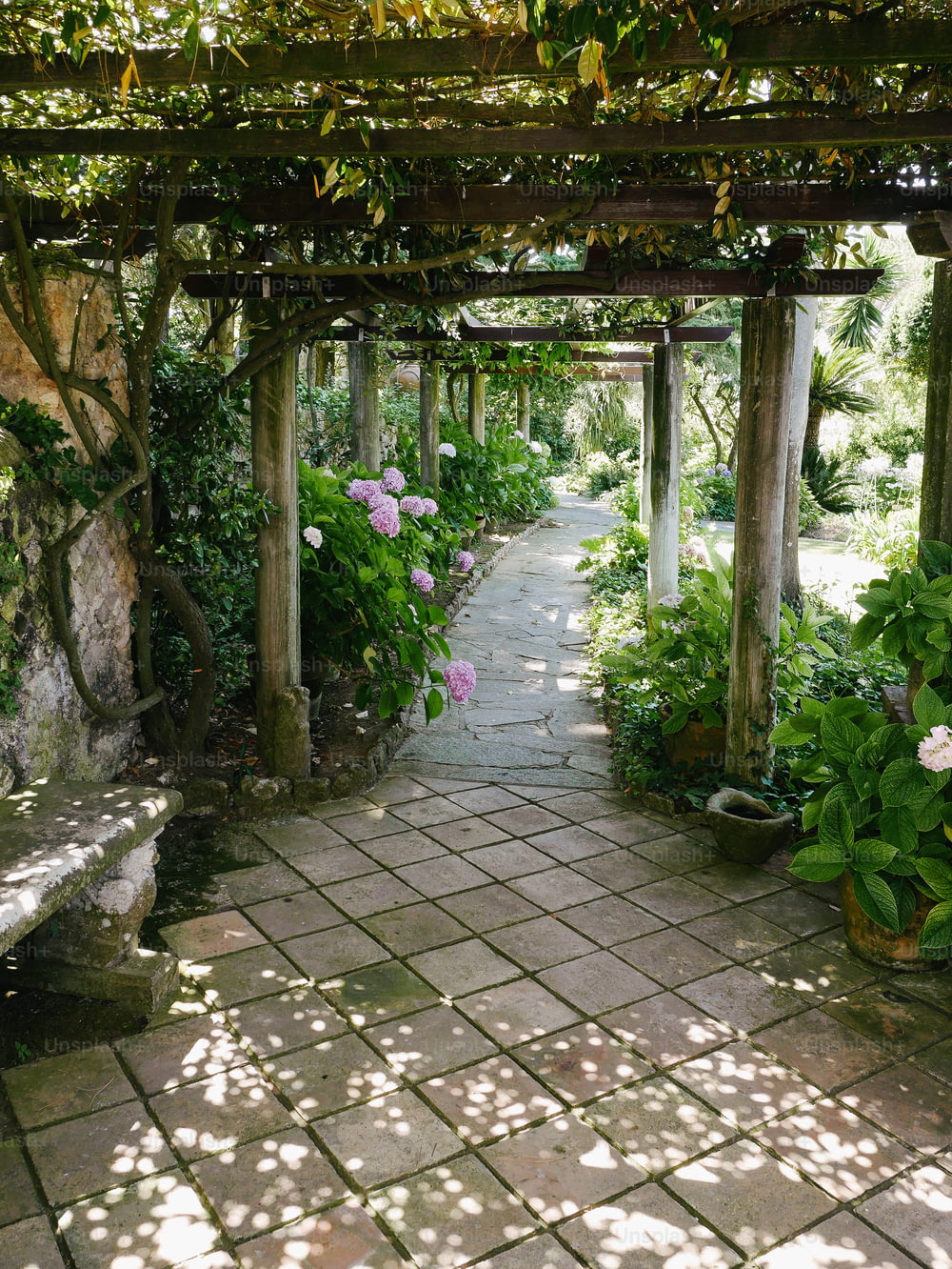 a stone walkway with a bench and flowers