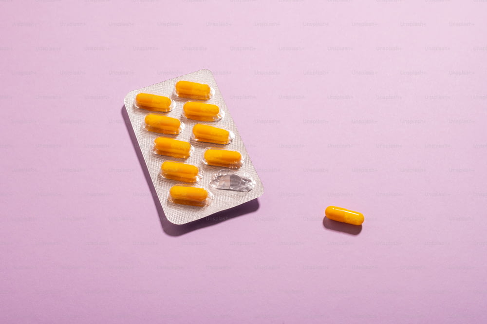 um pacote de pílulas sentado em cima de uma superfície roxa