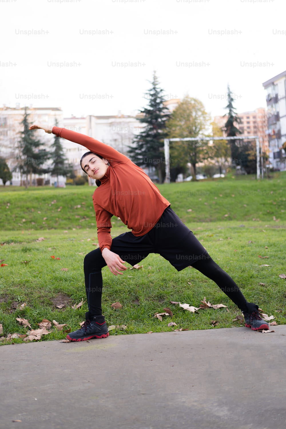 a man in a red shirt is doing a yoga pose