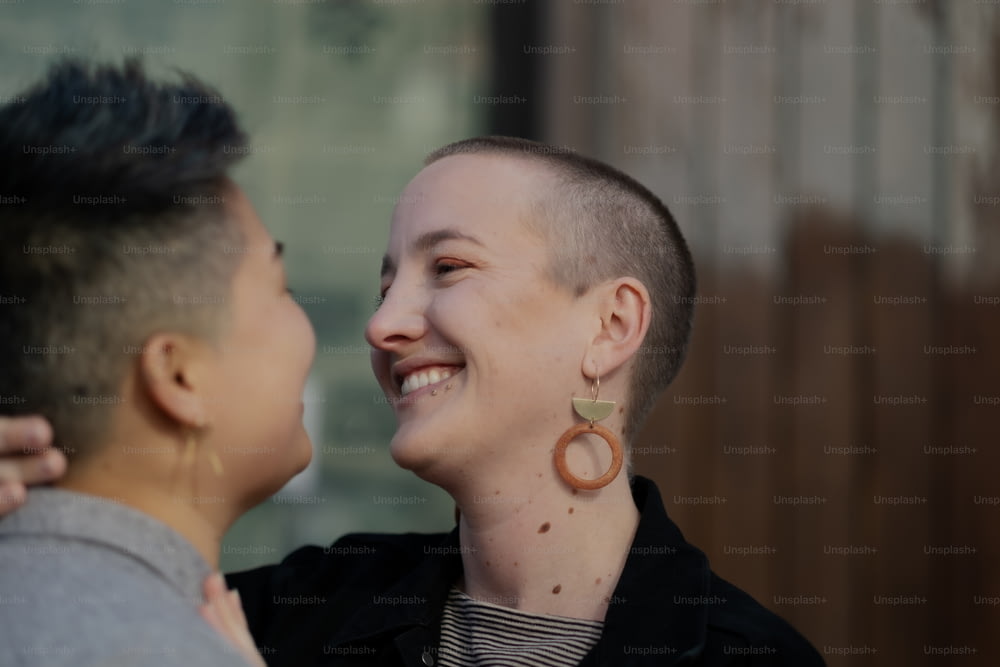 a woman with a shaved head smiles at a man