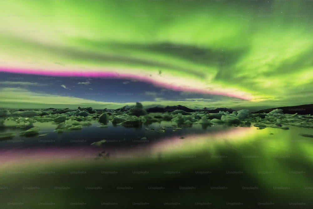 a green and purple aurora bore over a body of water