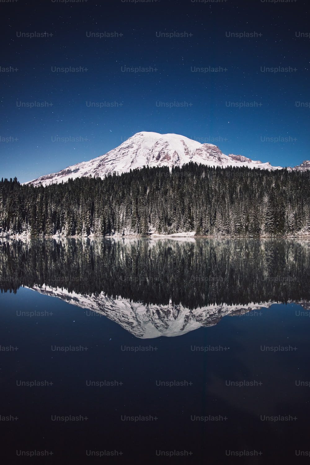 a snow covered mountain is reflected in the still water of a lake