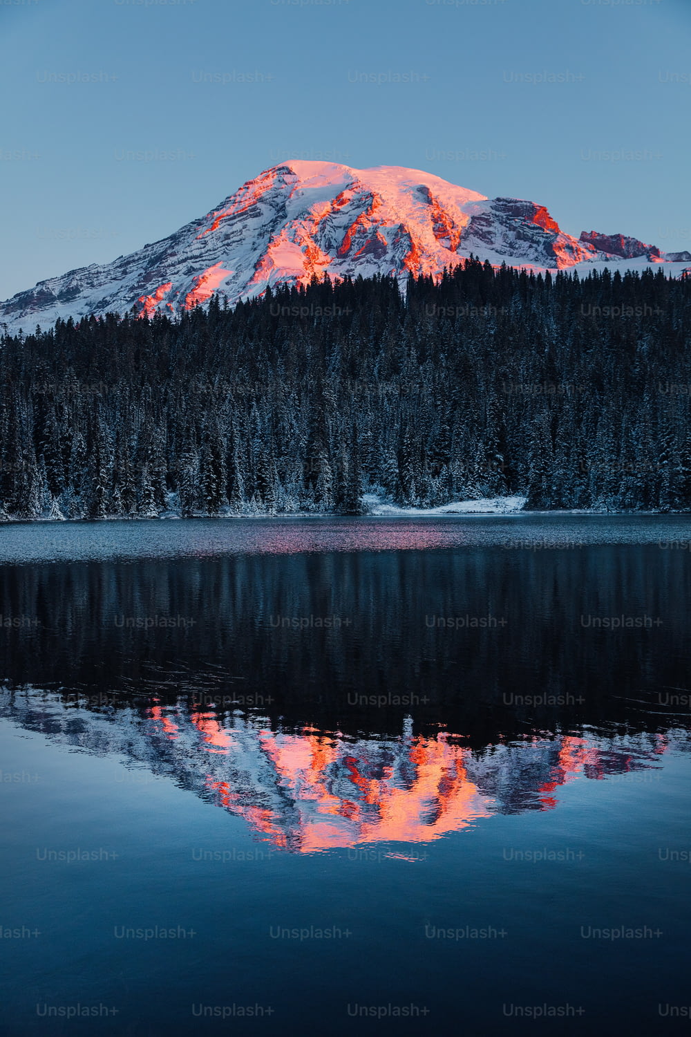uma montanha é mostrada com um lago em frente a ela
