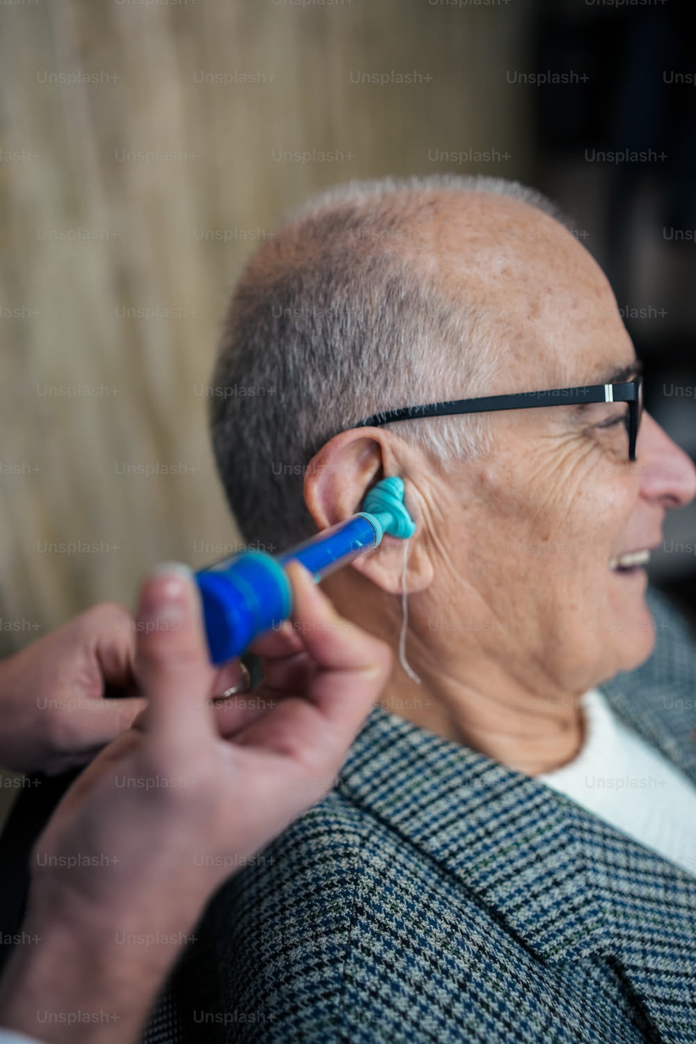 an older man getting his ear checked by a doctor