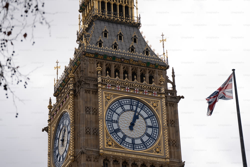 Una torre dell'orologio con una bandiera britannica che sventola sullo sfondo