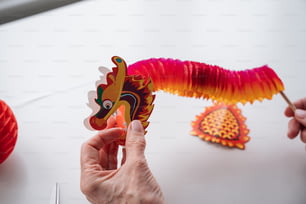 a person holding a dragon shaped paper decoration