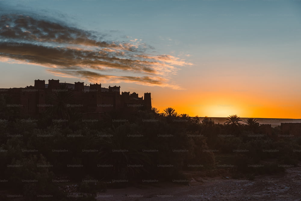 the sun is setting behind a castle on a hill