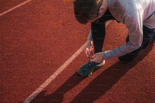 a man tying a pair of shoes on a tennis court