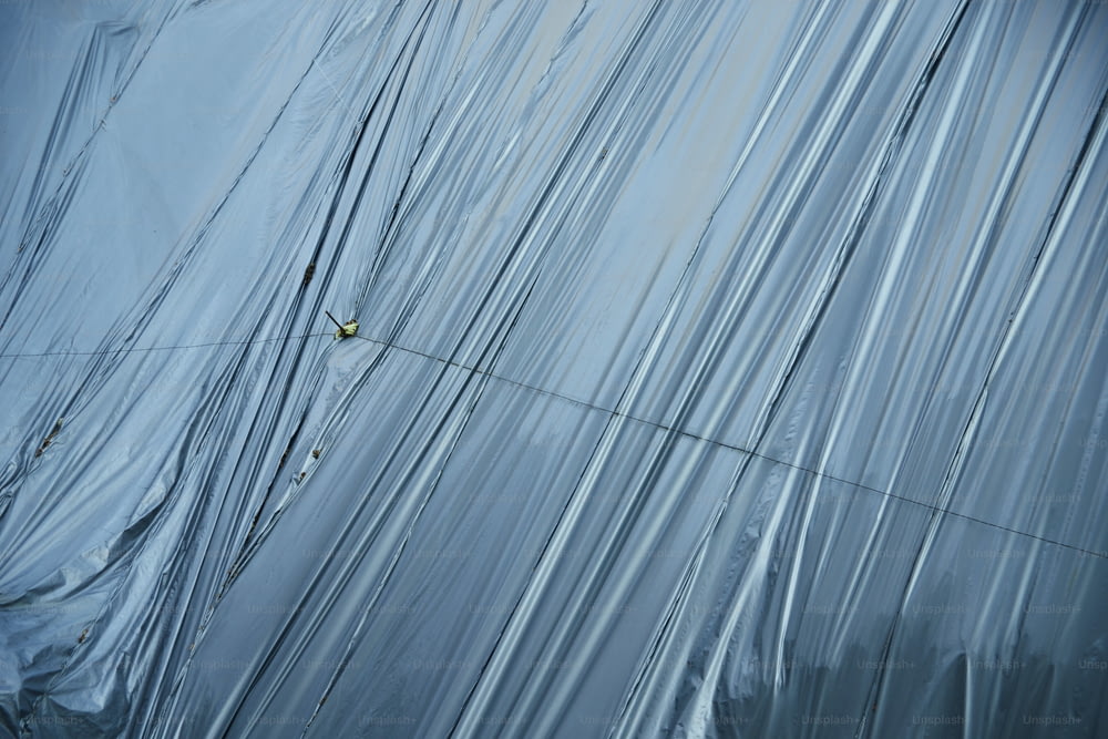 um homem subindo a lateral de um prédio coberto de plástico
